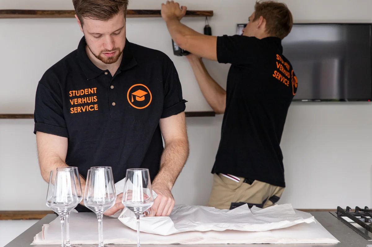 Verhuizer Budget Verhuisservice tilt een ingepakte verhuisdoos in de verhuiswagen